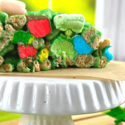 Lucky Charms St Patrick’s Day Rice Krispies Treats on a white plate in front of a window