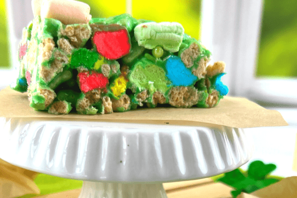 Lucky Charms St Patrick’s Day Rice Krispies Treats on a white plate in front of a window