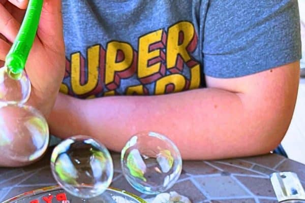 Best DIY Bubble Solution To Make At Home child blowing homemade bubbles with a straw