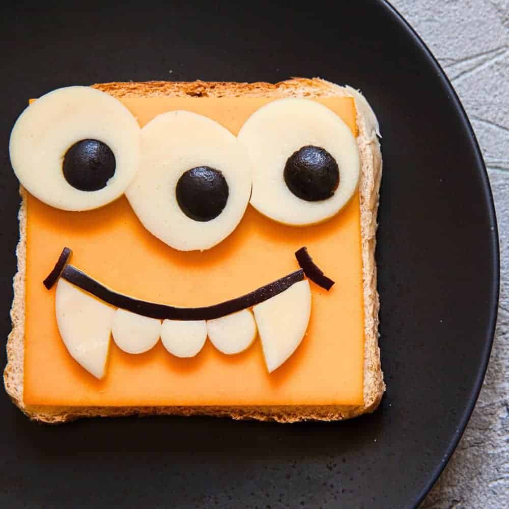 Build Your Own Silly Monster Face Halloween Toast - toast with a slice of cheese and then a Halloween monster face made out of cheese and black olives