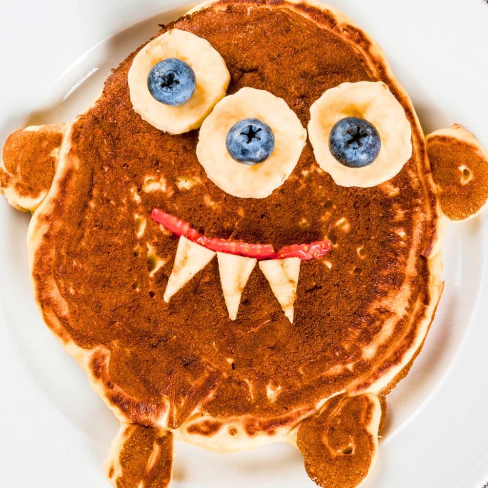 Halloween Monster Pancakes pancake with silly monster face made from fruit for a Halloween breakfast for kids