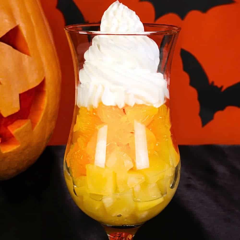 Healthy Candy Corn Halloween Breakfast Parfait Recipe on table with a Halloween pumpkin in background