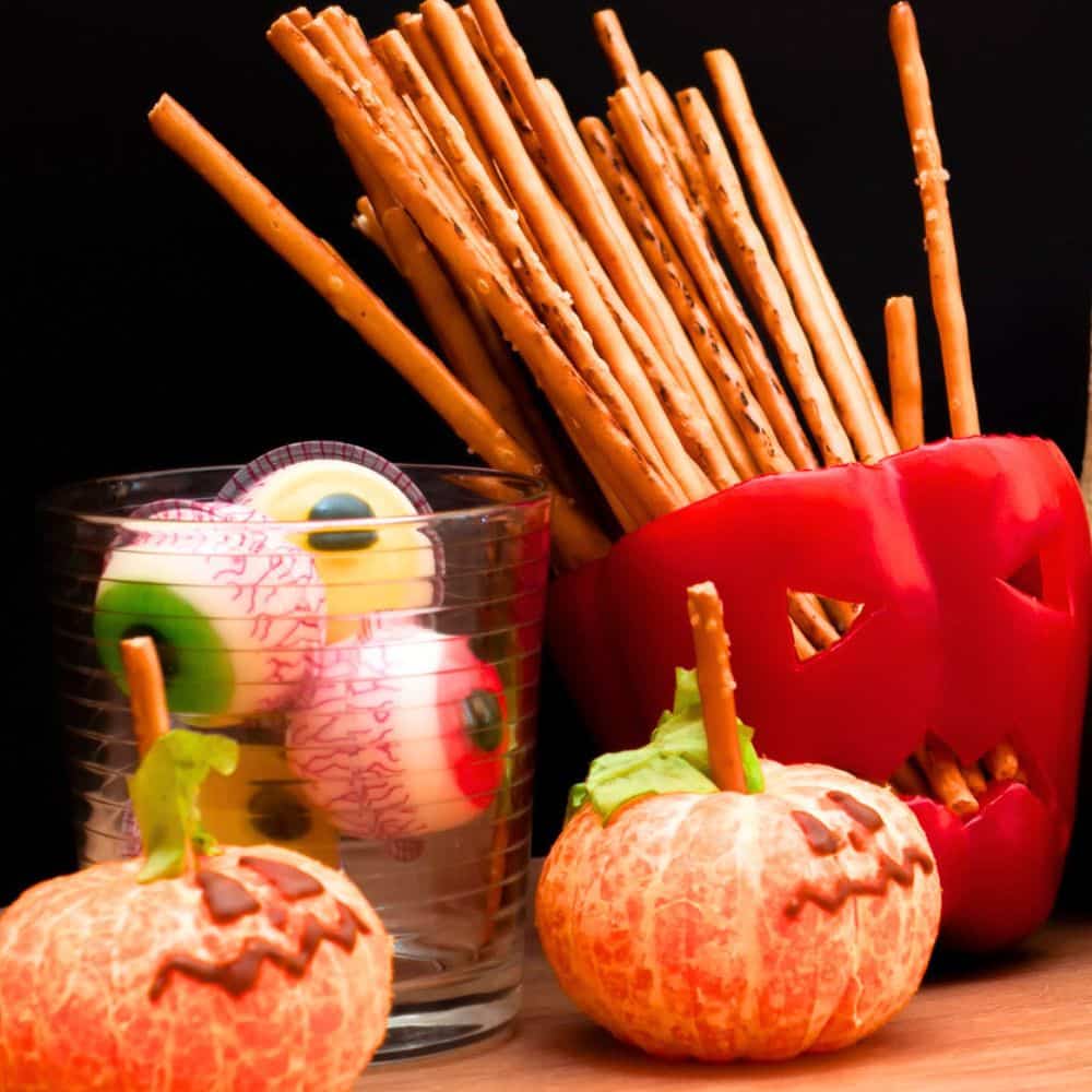 Healthy Halloween Snacks For Kids (Pumpkin Peppers and Pumpkin Oranges) red pepper cut out with pumpkin face and breadsticks in the top for hair and peeled oranges with a chocolate face drawn on to look like mini pumpkins