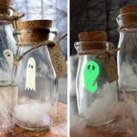 DIY Glowing Pet Ghost In A Jar Craft For Kids 2 pictures of bottle ghost crafts one with glowing ghosts in a jar and the other with light jar ghost both in front of a spooky Halloween moon window