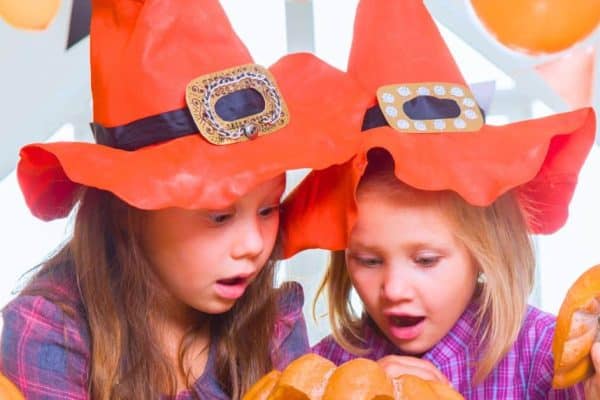 Fun Witch Themed Halloween Games (Witch Activities For Kids) 2 girls dressed in witch hats playing a witch game at a party