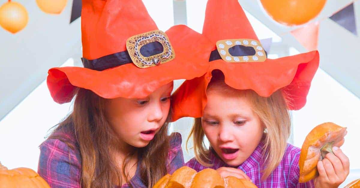 Fun Witch Themed Halloween Games (Witch Activities For Kids) 2 girls dressed in witch hats playing a witch game at a party