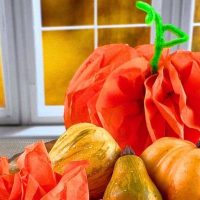 DIY Tissue Paper Pumpkin Craft pumpkin made of tissue paper sitting on a table in front a window with fall leaves in the background