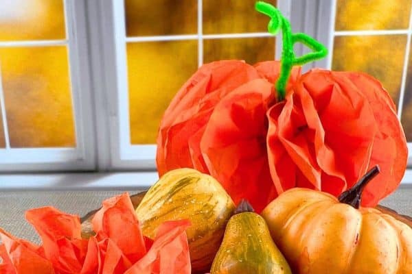 DIY Tissue Paper Pumpkin Craft pumpkin made of tissue paper sitting on a table in front a window with fall leaves in the background
