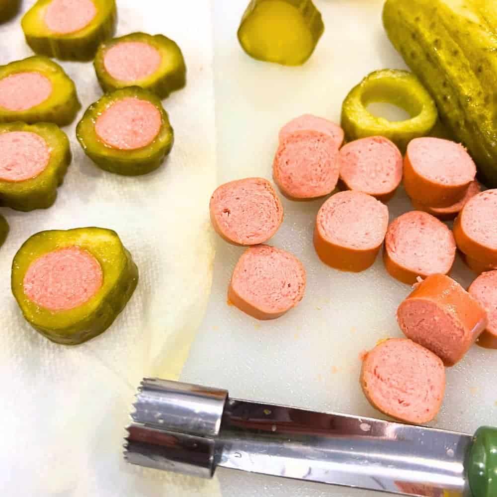 Dilly Dog Bite Recipe Tips for Hot Dog Pickles - dill pickles pieces and hot dog pieces on a cutting board with an apple corer