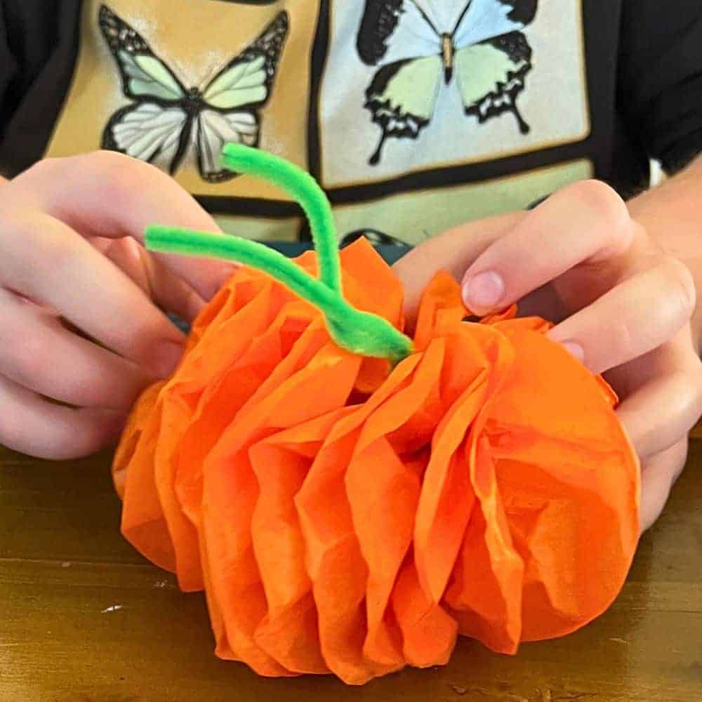 Tissue Paper Pumpkins Craft hands of child making a pumpkin out of tissue paper