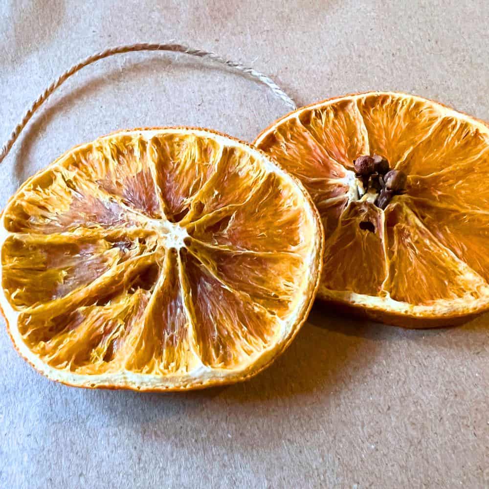 Dried Orange Ornaments and Fruit Garland Tutorial Step By Step - 2 dried oranges slice ornaments with jute twine through them on butcher block paper