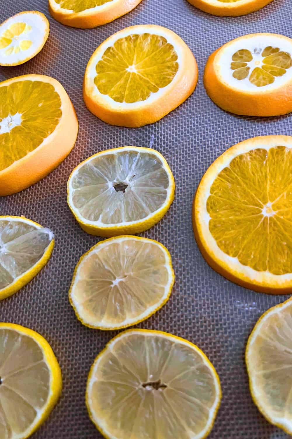 How To Make Citrus Ornaments Drying Oranges For Holiday Decor - fresh orange slices on a non stick mat on a cooking sheet for drying oranges in the oven