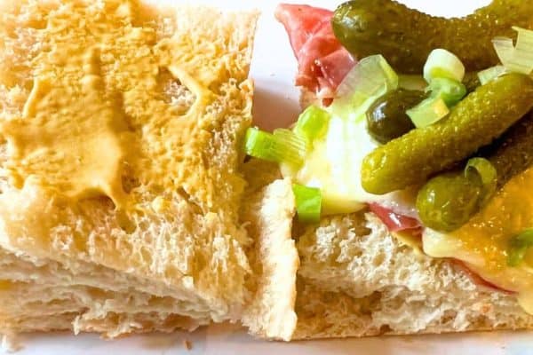 Cheese Raclette Sandwich With Prosciutto Recipe open raclette grilled cheese on a white plate