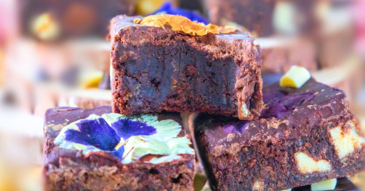 Dark Chocolate Brownies With Edible Flowers stacked on each other