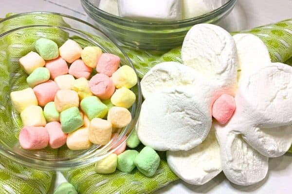 Easy Marshmallow Flowers Video and Step-By-Step Pictures white marshmallow flower on a green napkin with small colored marshmallows in a bowl next to it