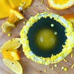 Solar Splash Eclipse Party Punch Drink For Kids - black punch with a round orange juice ice cube in a glass with a yellow sprinkles rim