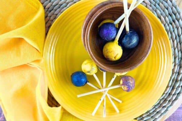 Easy Solar Eclipse Suckers Galaxy Lollipops on a yellow plate and in a brown bowl on a table with a yellow napkin