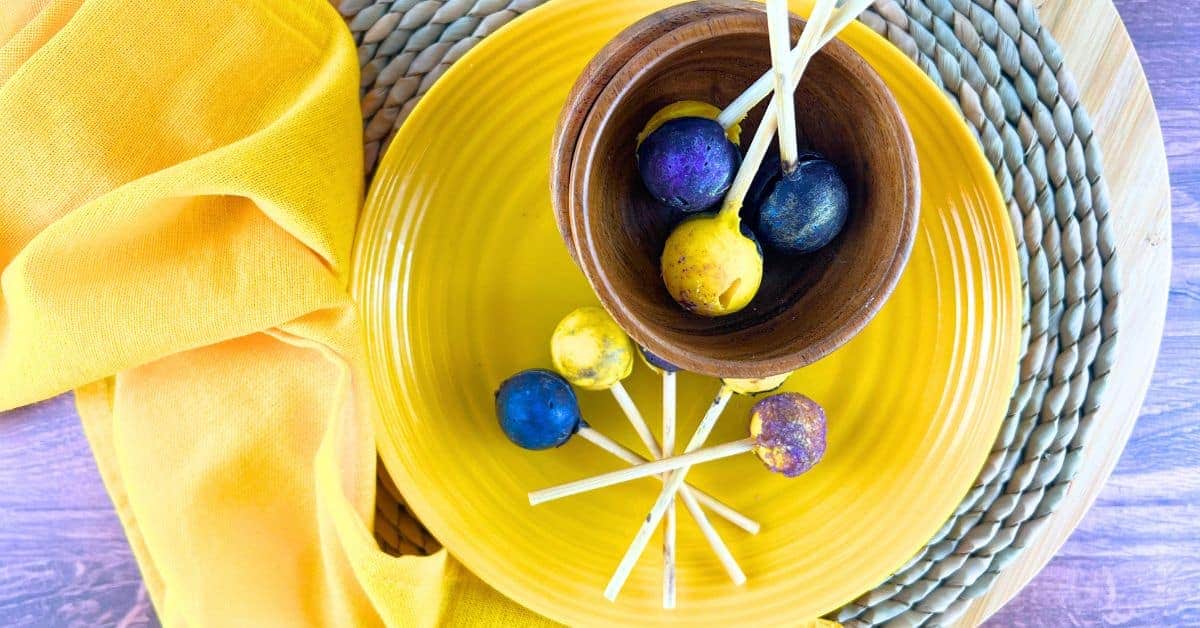 Easy Solar Eclipse Suckers Recipe for Galaxy Lollipops on a yellow plate and in a brown bowl on a table with a yellow napkin