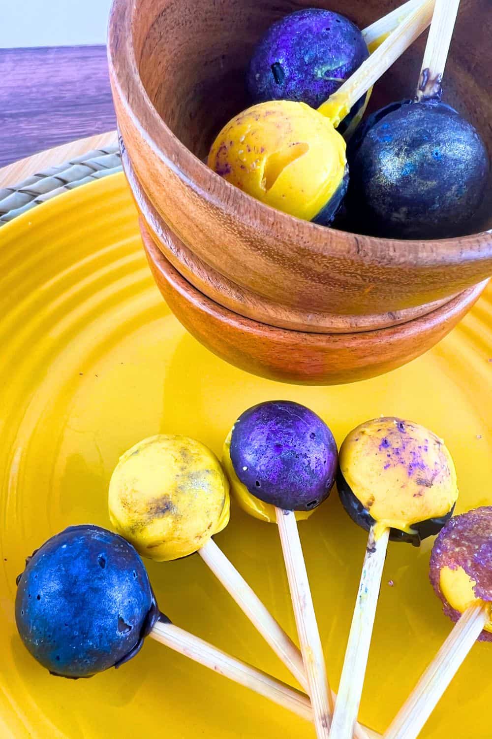 How To Make Chocolate Eclipse Suckers - round chocolate suckers of different galaxy colors on a yellow plate on a table