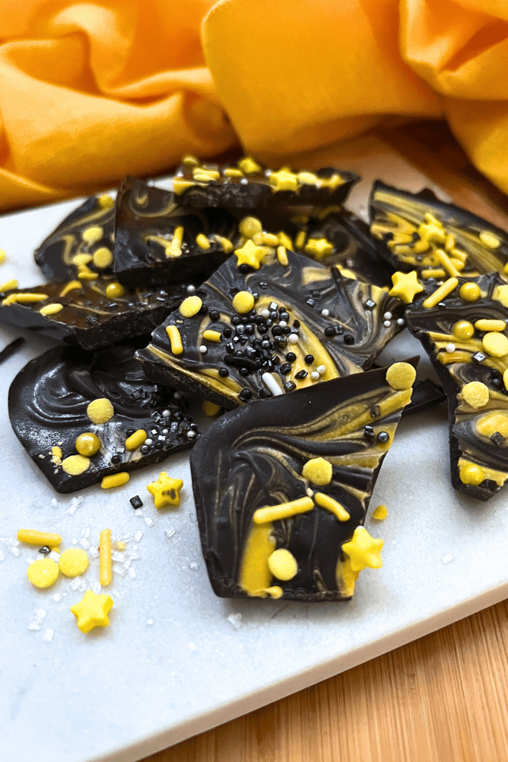 How To Make Eclipse Bark Candy (CHOCOLATE CANDY BARK) solar eclipse bark candy on a white serving platter with yellow napkin behind it