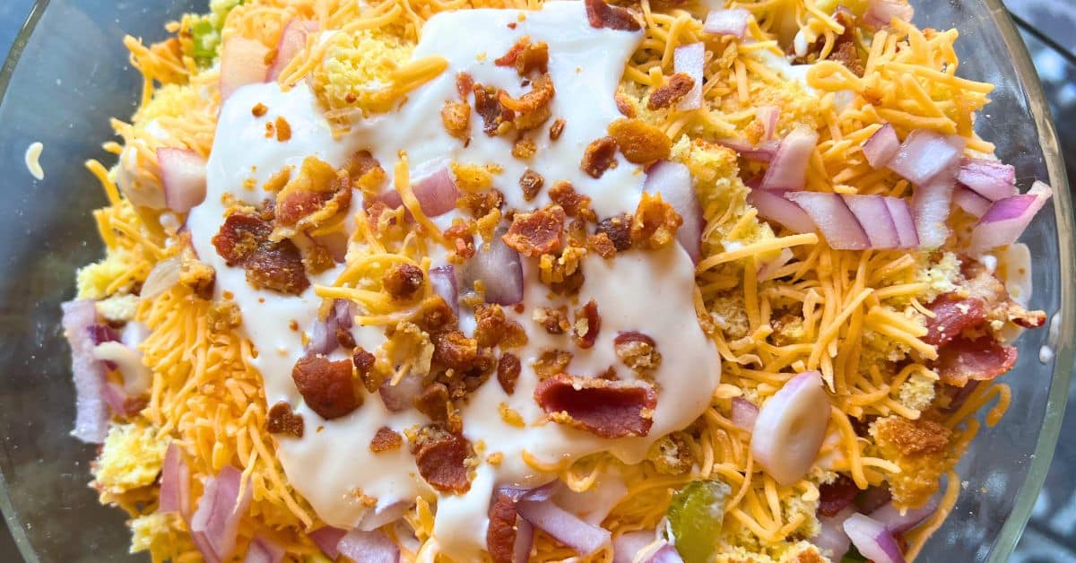 Southern Cornbread Salad Recipe top down view of cornbread salad topped with dressing and crumbled bacon in a bowl