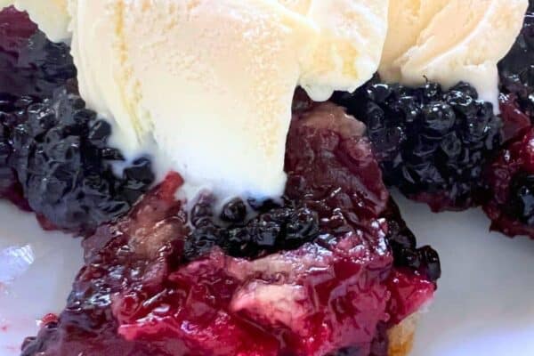 Homemade Blackberry Cobbler Recipe in a white bowl with vanilla ice cream on top