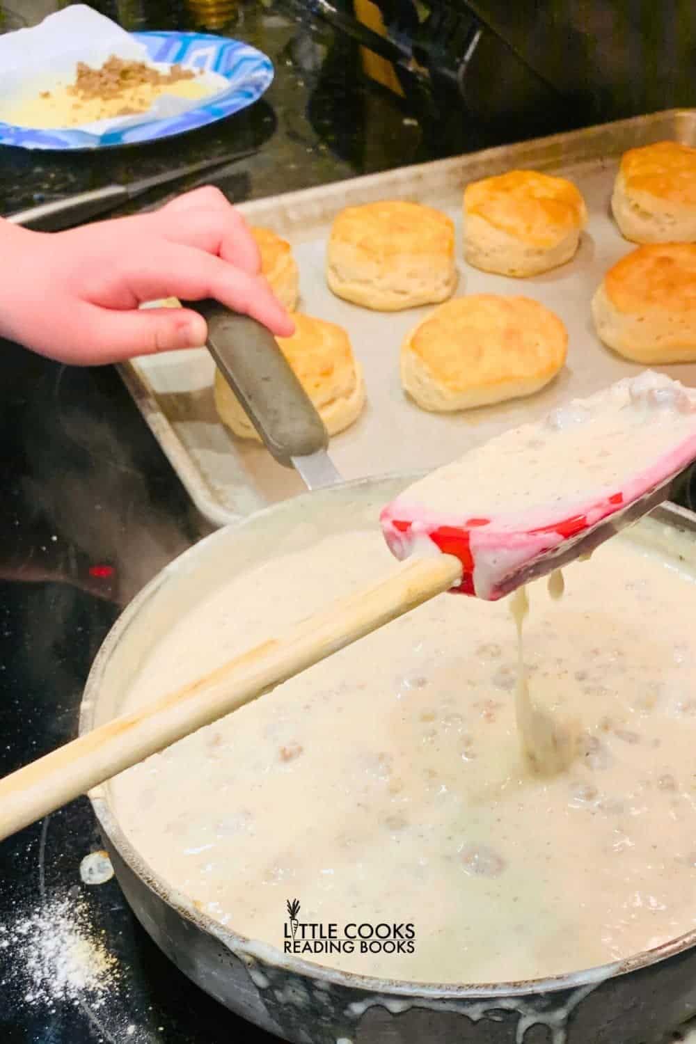 Biscuits And Gravy Recipe sausage gravy on stove top with Southern style biscuits on baking sheet next to it