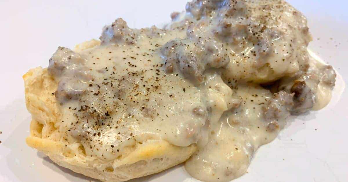 Traditional Southern Recipe For Sausage Gravy - biscuits and homemade white gravy with sausage on a white plate