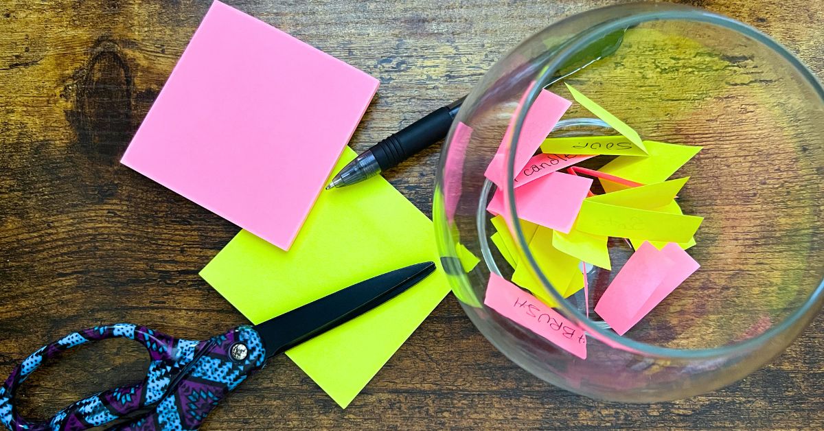 How To Play The FishBowl Game Rules Tips Fun Party Game For Big Groups and Family Game Night - small fish bowl with strips of colored paper words sitting on a table with game supplies