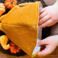 Stuffed Turkey Game - Thanksgiving games for family fun - child's hand reaching into a turkey hat turkey game on thanksgiving table decor