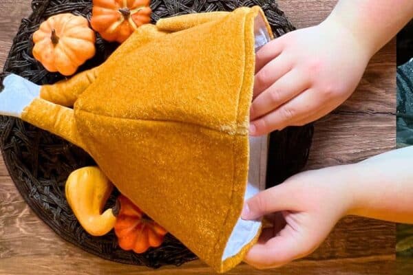 Stuffed Turkey Game - Thanksgiving games for family fun - child's hand reaching into a turkey hat turkey game on thanksgiving table decor