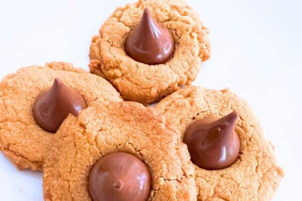 4-Ingredient Peanut Butter Kiss Cookies - Hershey kiss cookies (or peanut butter blossom cookies) on white plate. Great for Christmas cookies, dessert tables or party foods.