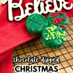 Dipped Christmas Oreos Are the perfect holiday treat - Green Chocolate Dipped Christmas Oreos on a cooling rack with a red Christmas napkin and a Believe Santa Sign for Christmas Food Desserts Classic Cookies