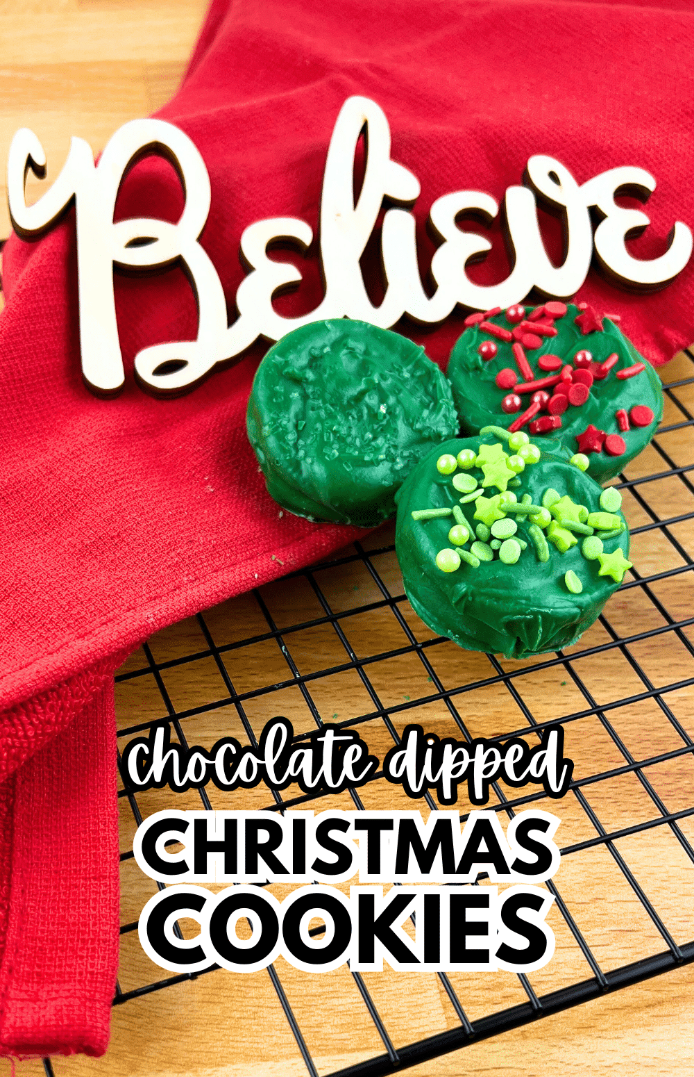 Dipped Christmas Oreos Are the perfect holiday treat - Green Chocolate Dipped Christmas Oreos on a cooling rack with a red Christmas napkin and a Believe Santa Sign for Christmas Food Desserts Classic Cookies