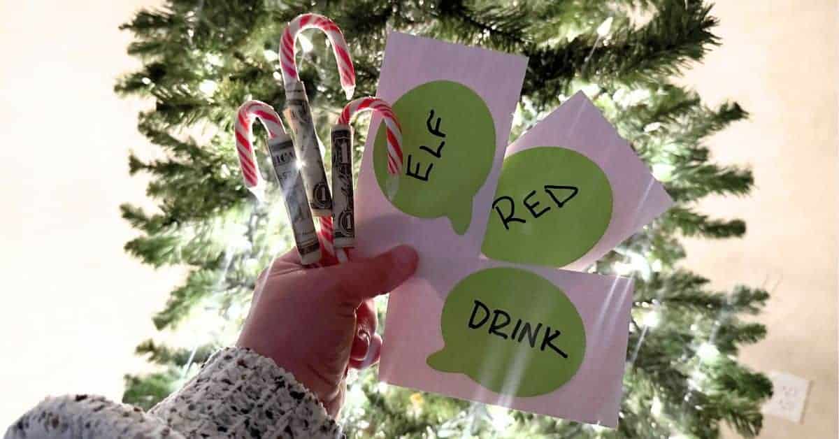 Hilarious Peppermint Payout Candy Cane Dollar Game For Christmas for Funny Candy Cane Olympic, Fun Christmas Party Games or Holiday Ice Breaker Games for Group Games - hand holding candy cane dollar bill christmas games in front of christmas tree