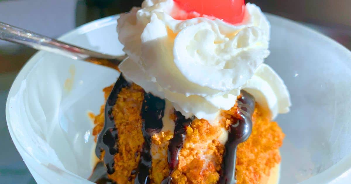 Cinco De Mayo Mexican Fried Ice Cream Dessert - air fried Mexican ice cream drizzled with chocolate and topped with whipped cream and cherry in a dish for Cinco de Mayo party desserts or fiesta party foods Mexican recipes