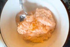 orange fluff salad (orange creamsicle salad recipe) in a white bowl with a spoon